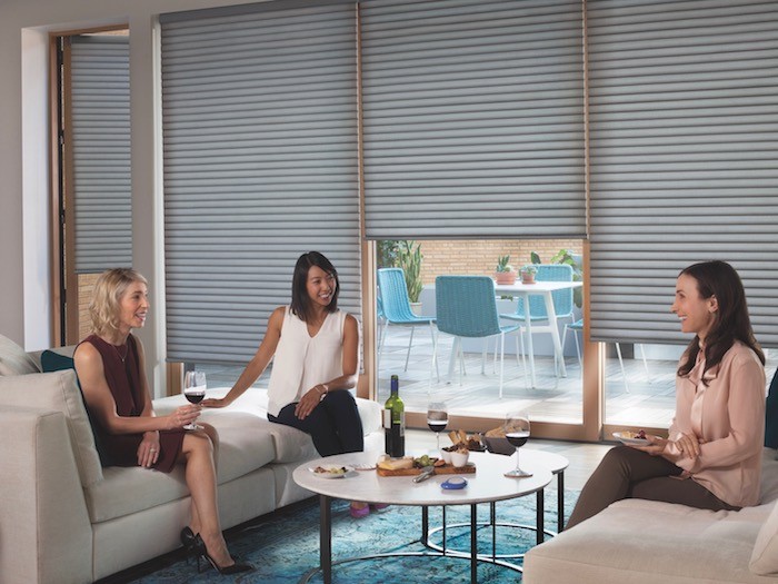 Three women sitting around coffee table drinking wine.